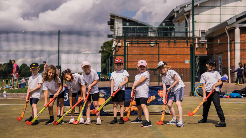 Children smiling with hockey sticks at a festival